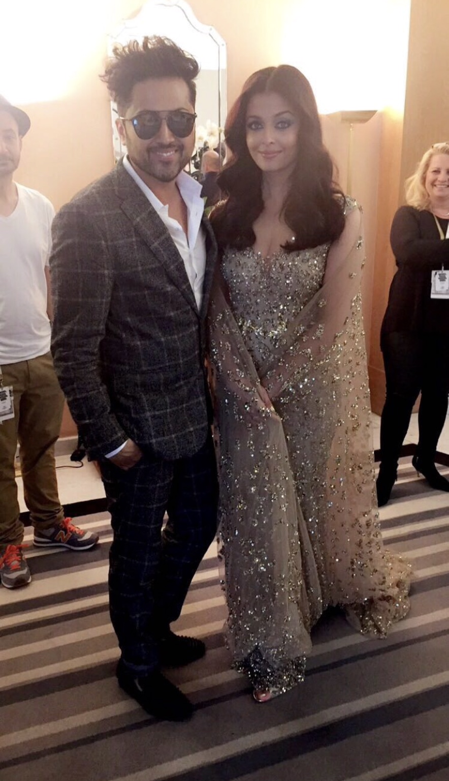 Aishwarya Rai in einer hellen, reich verzierten Robe von Ali Younes Couture neben Samuel Sohebi in einem karierten Anzug.